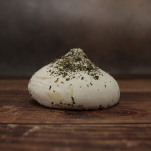 Photo de face d'un fromage en forme de meringue blanche, saupoudré de basilic.